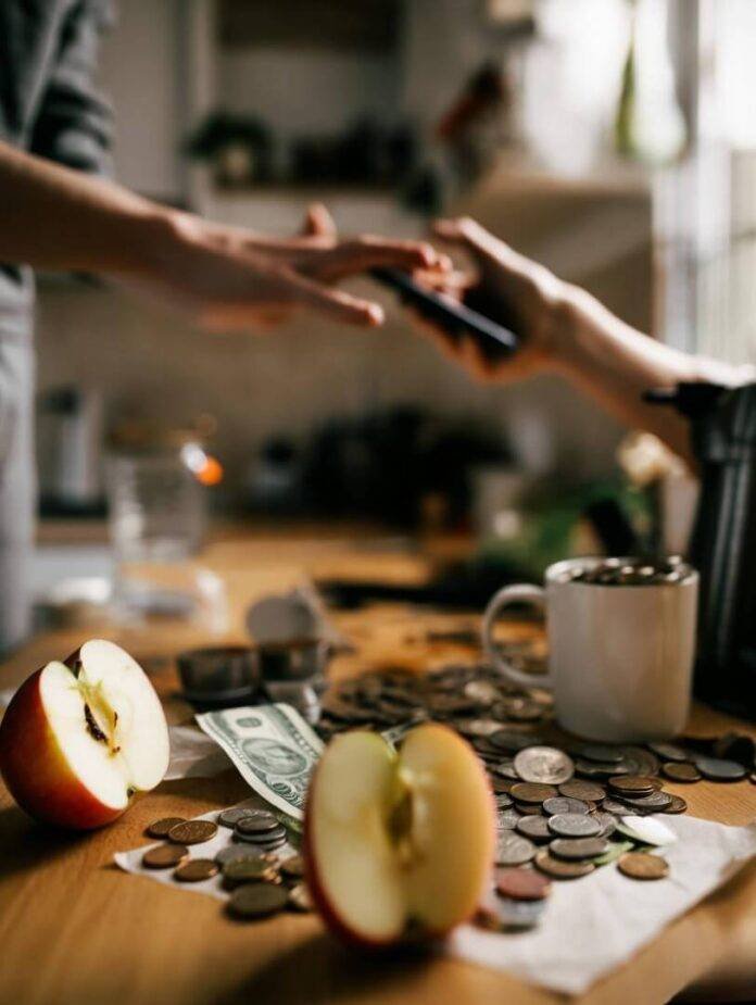 Messy kitchen coins spill, half-eaten apple nearby.